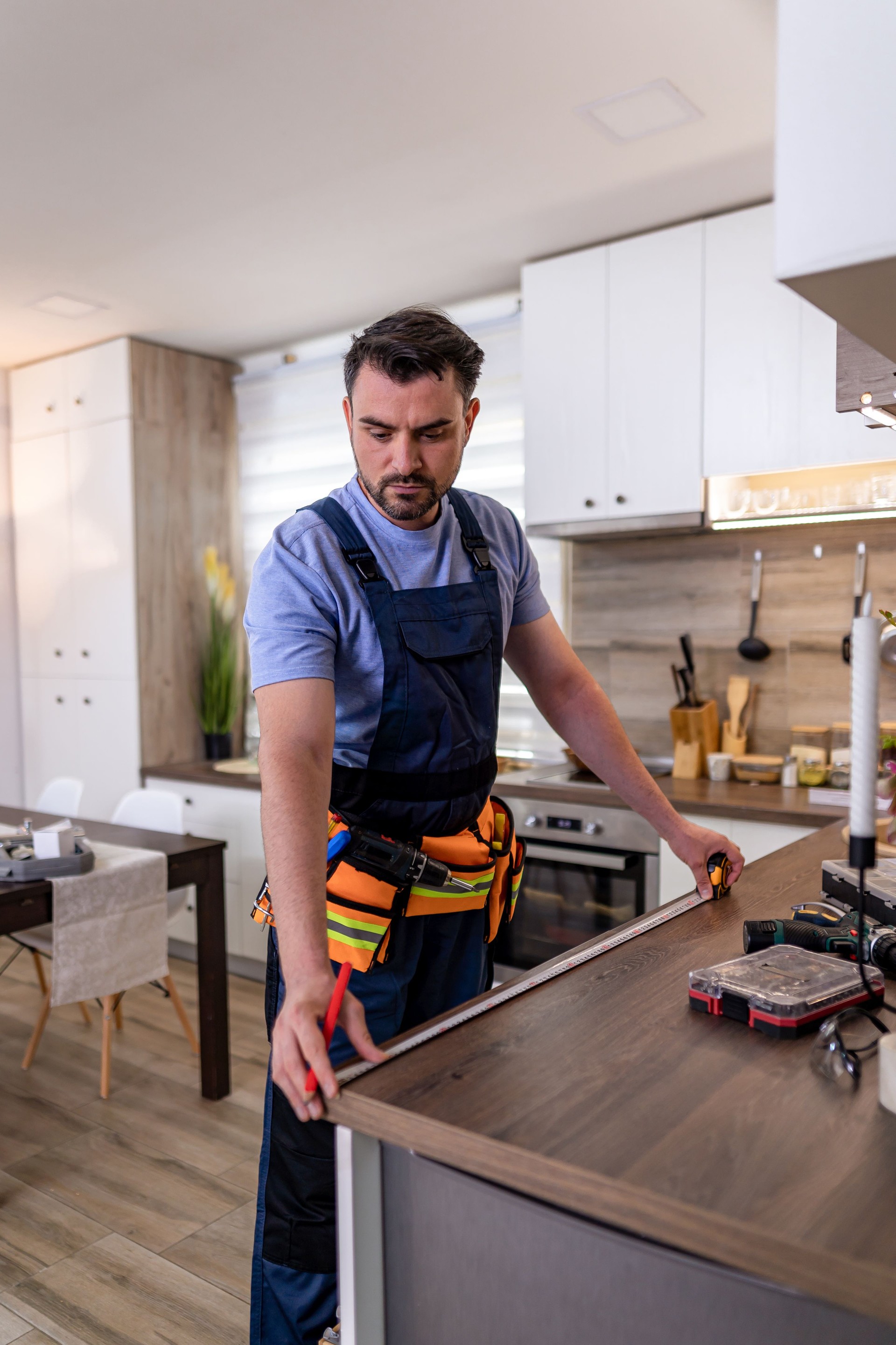 Skilled worker installing kitchen cabinetry in modern home during daylight hours